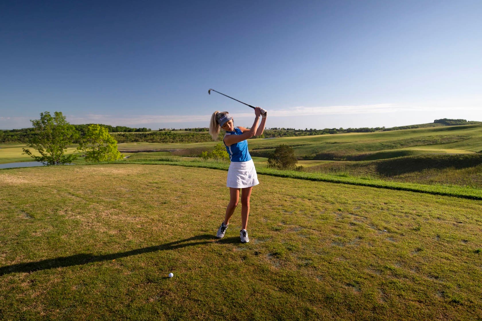 Golfer mid-swing on a Big Cedar Lodge championship course with the Ozark hills behind