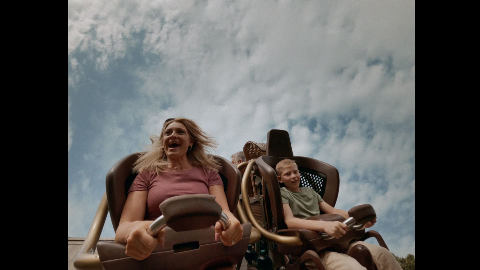 Guests riding a Silver Dollar City coaster beneath a bright sky