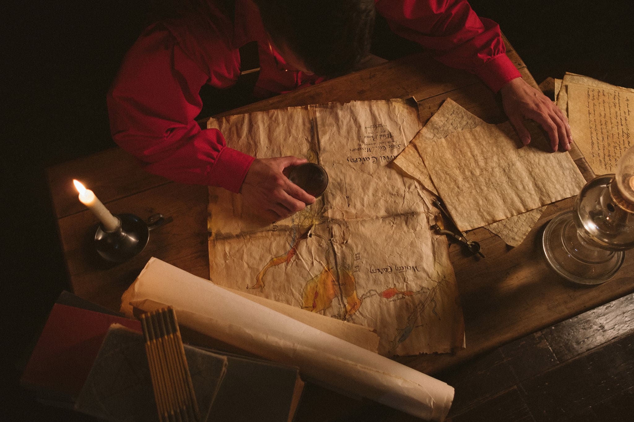 Period cartographer scene with a hand-drawn Marvel Cavern map, candle, and oil lamp