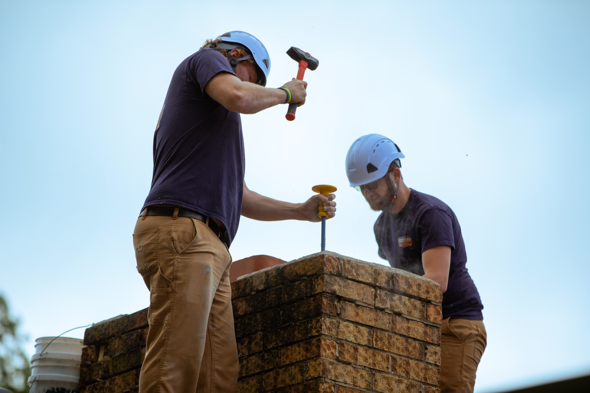 Two SureGlow technicians repairing a brick chimney crown